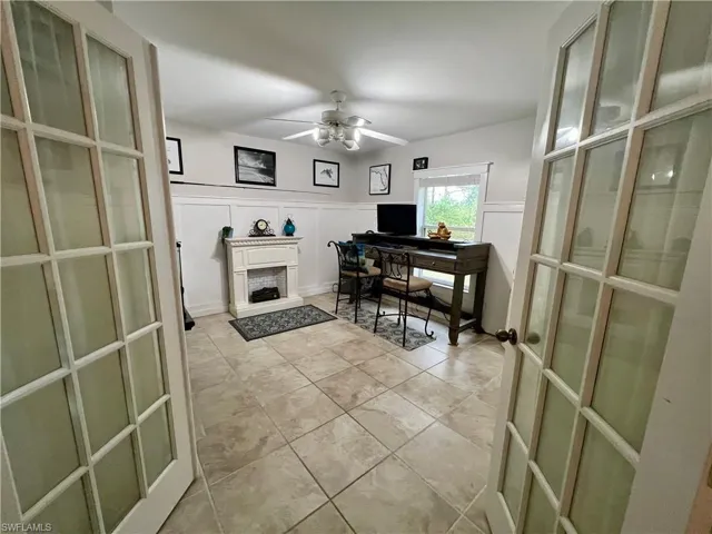 Home office with ceiling fan and French doors.
