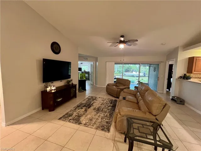 Living room with ceiling fan, light tile patterned flooring, and cathedral ceilings