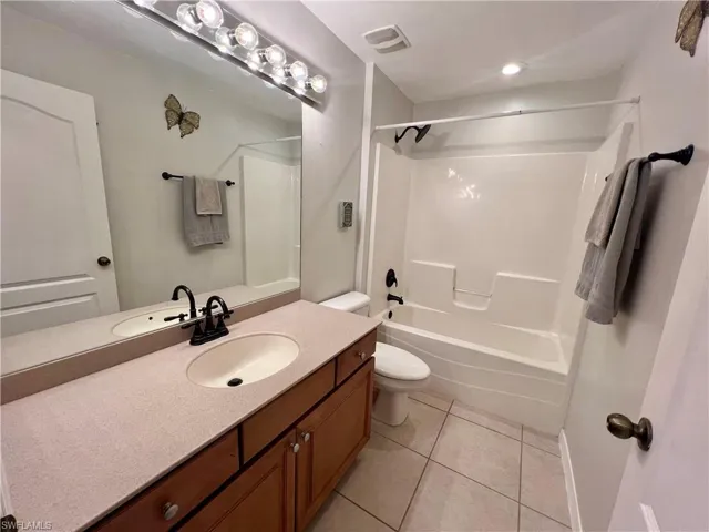 Full bathroom featuring toilet, vanity, tile patterned flooring, and tub / shower combination