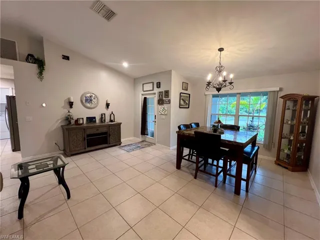 Tiled dining room featuring cathedral ceilings and an inviting chandelier