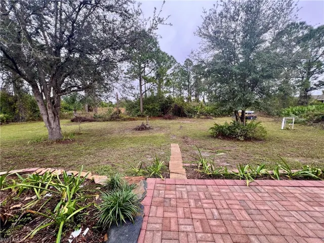 View of spacious backyard with pavers on open patio.