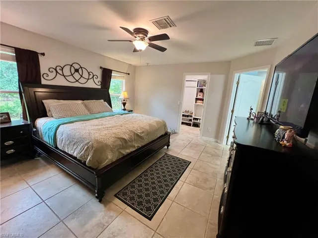 Primary bedroom with ceiling fan, light tile patterned floors, and a walk in closet