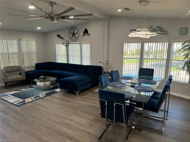 Dining space featuring ceiling fan with notable chandelier, a wealth of natural light, and hardwood / wood-style floors