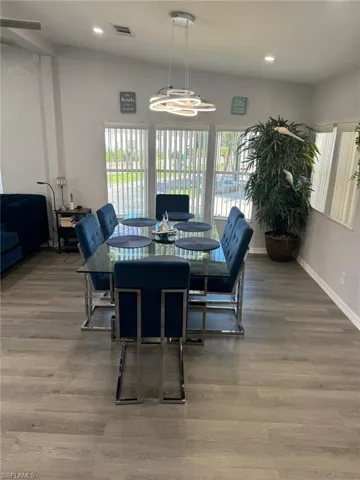 Dining area with lofted ceiling, hardwood / wood-style floors, and a notable chandelier