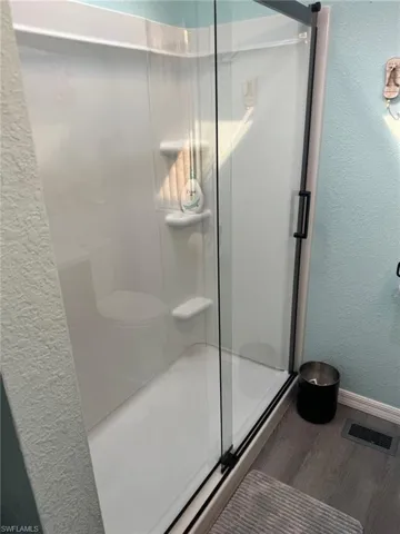 Bathroom featuring hardwood / wood-style flooring and a shower with shower door