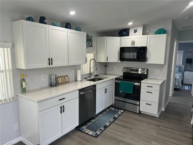 Kitchen featuring white cabinets, appliances with stainless steel finishes, wood-type flooring, and sink