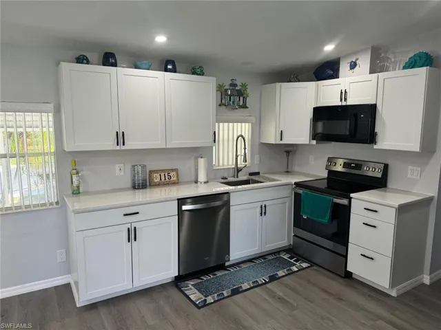 Kitchen featuring appliances with stainless steel finishes, white cabinetry, dark hardwood / wood-style flooring, and sink