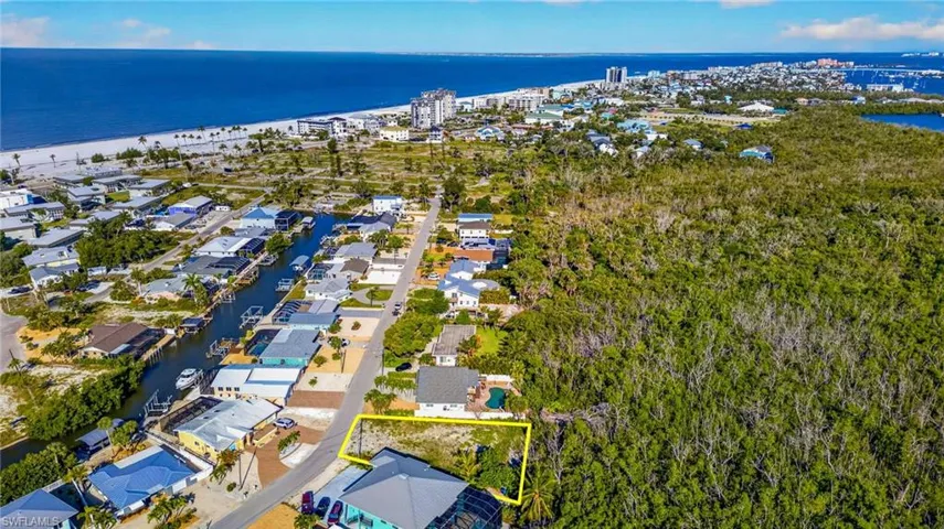 Cleared lot with direct road frontage, situated among residential properties and dense natural foliage - Virtually Edited Image