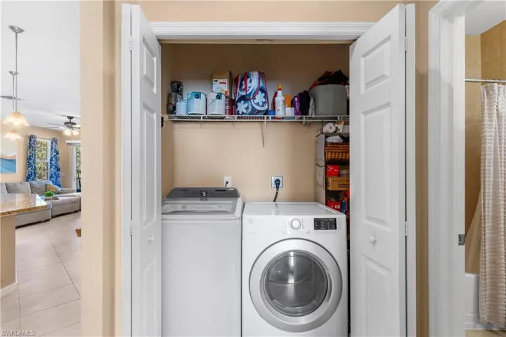 Dedicated laundry closet featuring a top-load washing machine, a front-load dryer, and a wire storage shelf