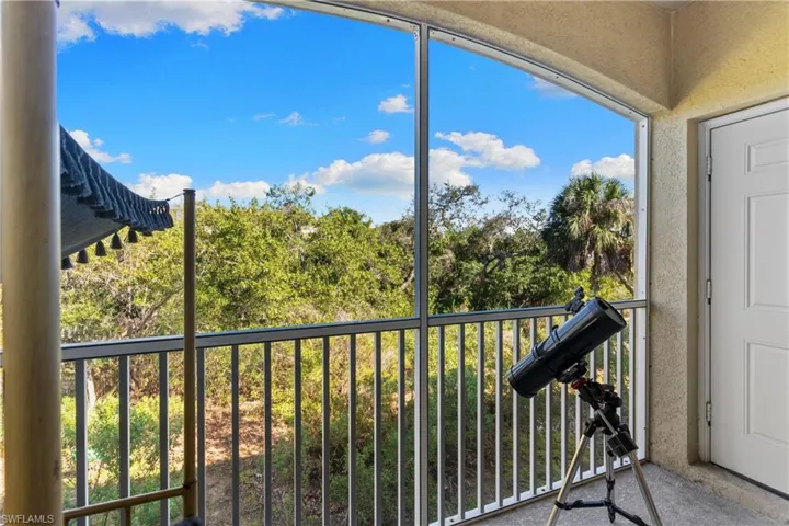 Screened balcony featuring a textured ceiling, stucco wall finish, and a white paneled door
