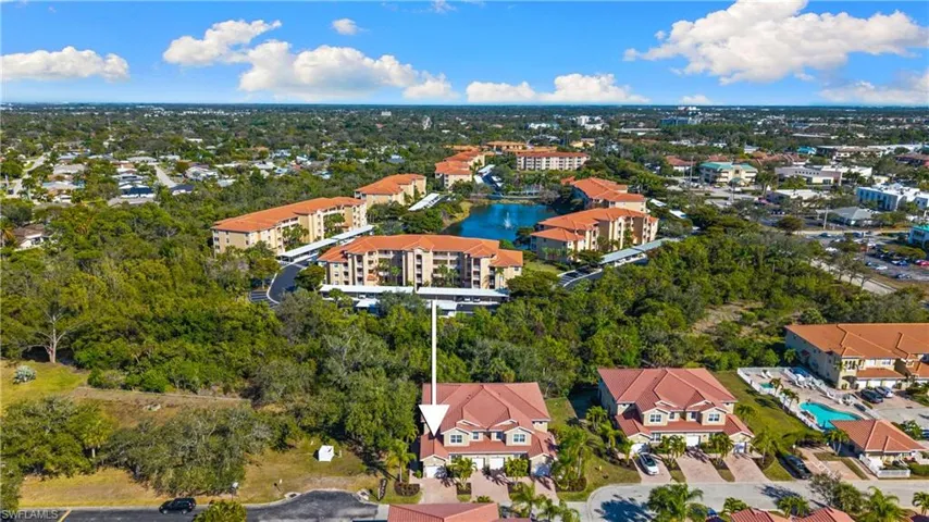 Aerial perspective highlighting the property with a red tile roof, beige exterior, and an attached garage