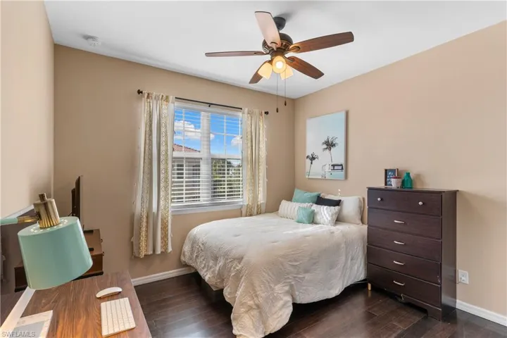 Bedroom featuring wood-finish flooring, a vaulted ceiling, a ceiling fan with integrated lighting, and a window with blinds and curtain rods