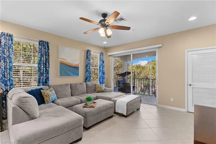 Living area featuring tile flooring, a ceiling fan with light fixture, recessed lighting, and sliding glass doors leading to a screened balcony