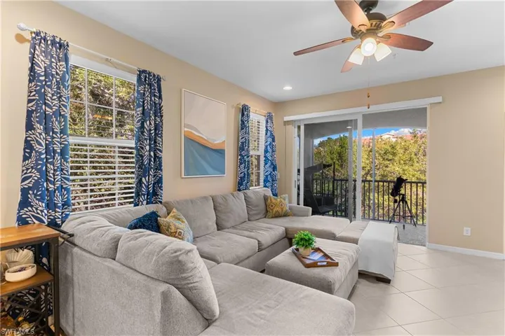Living area featuring a ceiling fan with light fixture, tile flooring, and a sliding glass door leading to a private balcony