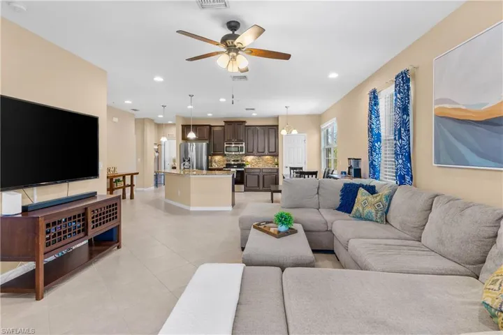 Open-concept living area featuring light-toned tile flooring, recessed lighting, and a ceiling fan