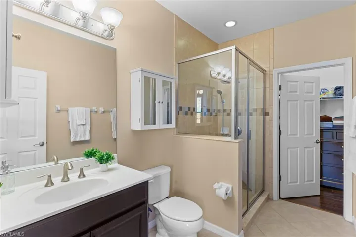 Contemporary bathroom featuring a glass-enclosed shower with tile surround, a single vanity with a white countertop and undermount sink, brushed nickel fixtures, and recessed lighting