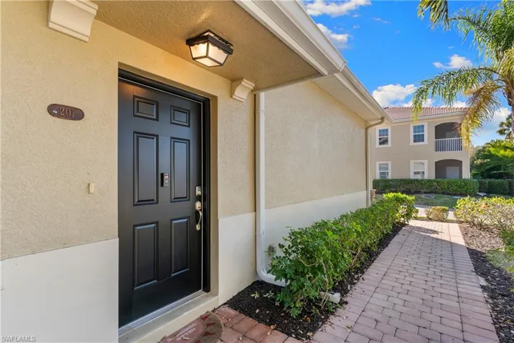 Entryway featuring a black paneled door with brushed nickel hardware, an overhead enclosed light fixture, and a textured stucco exterior