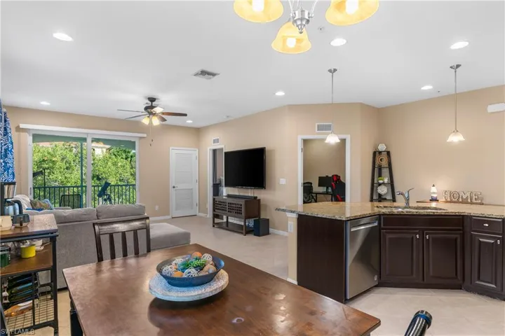 Open-concept living area featuring a kitchen with granite countertops, dark wood cabinetry, and stainless steel appliances
