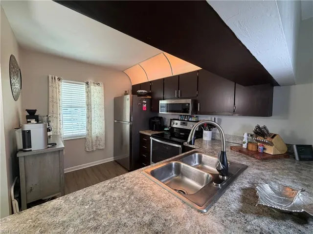 Kitchen featuring stainless steel appliances, dark wood-style floors, and light countertops