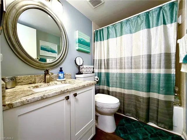 Full bathroom featuring vanity, shower / tub combo, and dark wood finished floors