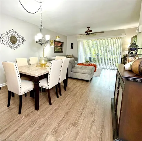 Dining space featuring light wood-style flooring, a ceiling fan, and a chandelier
