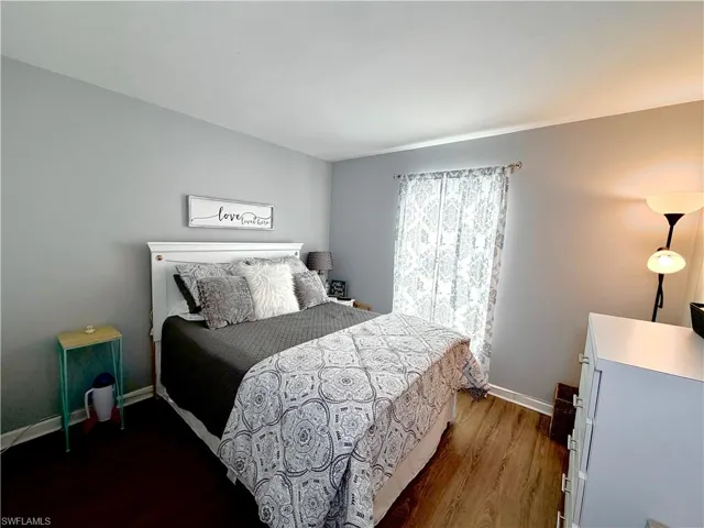 Bedroom with dark wood-style floors and baseboards
