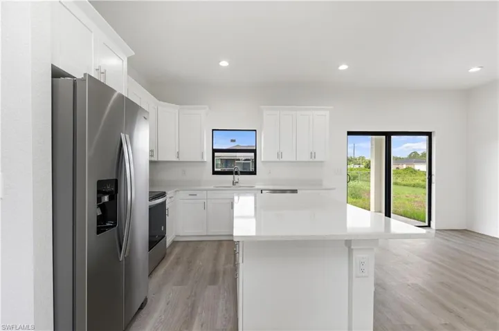 Kitchen featuring light hardwood / wood-style floors, white cabinetry, sink, and stainless steel fridge with ice dispenser