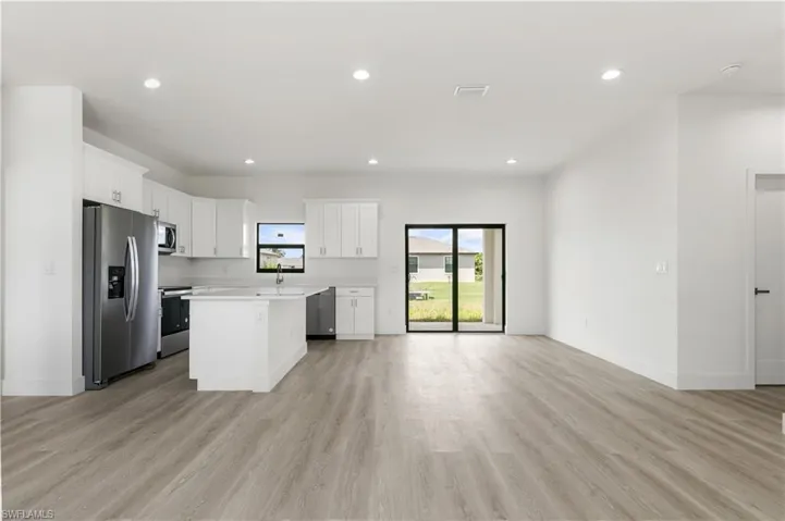 Kitchen featuring stainless steel appliances, light hardwood / wood-style floors, white cabinets, and a kitchen island