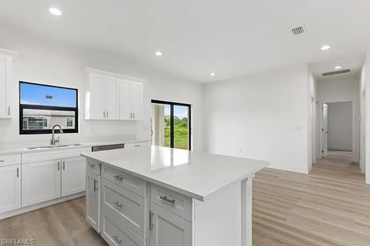 Kitchen with a kitchen island, sink, white cabinets, and light wood-type flooring