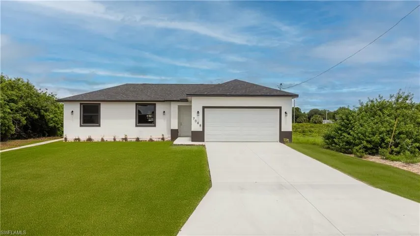 Ranch-style house featuring a garage and a front lawn