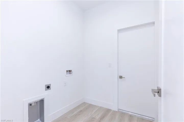 Clothes washing area with washer hookup, light hardwood / wood-style flooring, and hookup for an electric dryer