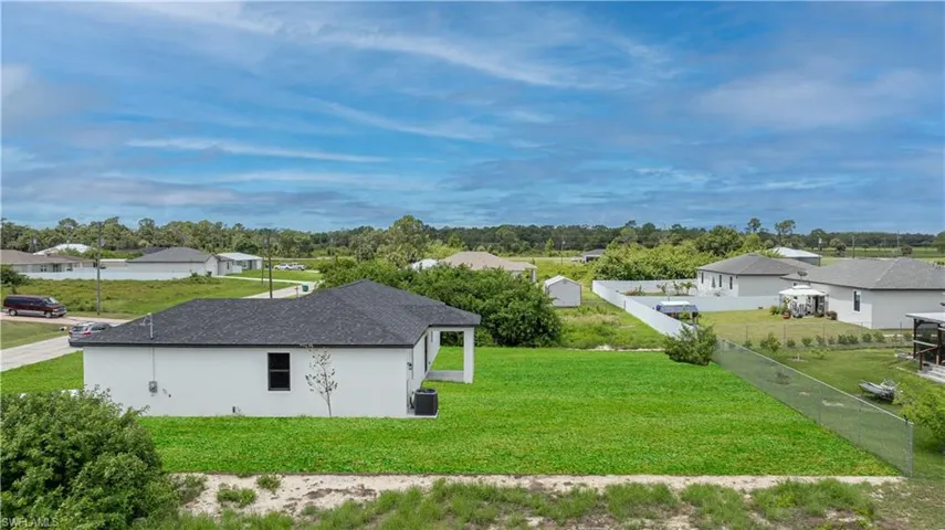 View of side of property with central AC unit and a lawn