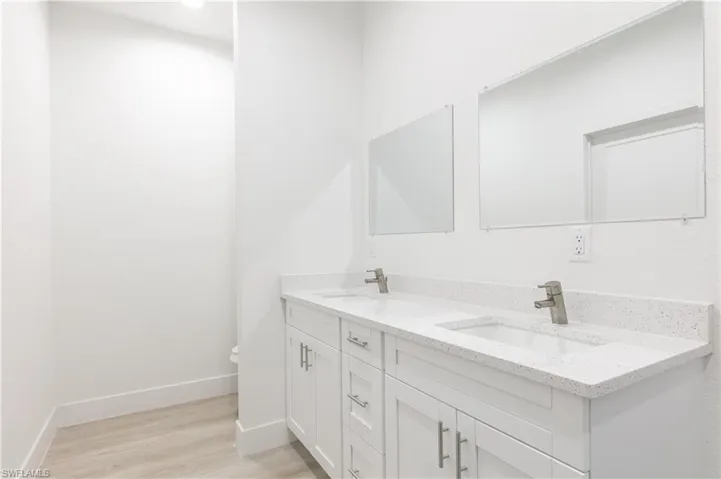 Bathroom with hardwood / wood-style flooring, vanity with extensive cabinet space, and dual sinks