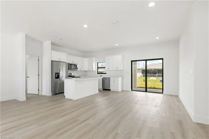 Kitchen featuring stainless steel appliances, white cabinetry, a center island, and light hardwood / wood-style flooring