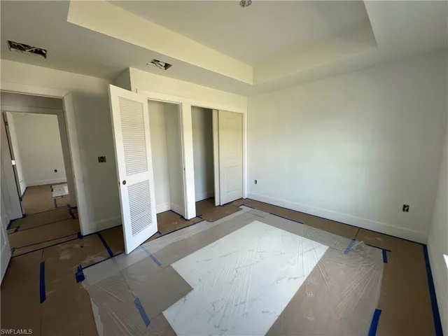 Tray ceiling, dual reach-in closets with louvered and solid-panel doors, and recessed ceiling lighting fixtures