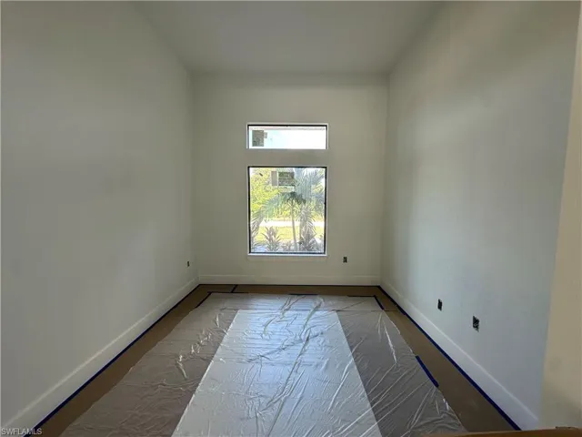 High-ceilinged room featuring neutral wall finishes, a large rectangular window, and an additional transom window