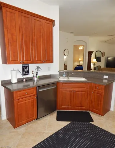 Kitchen with sink, light tile floors, and stainless steel dishwasher