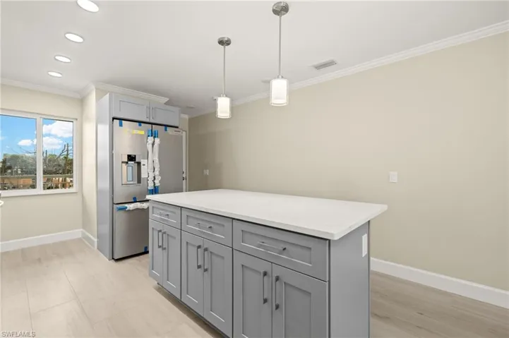 Kitchen featuring stainless steel appliances, light countertops, light wood-type flooring, a sink, and crown molding