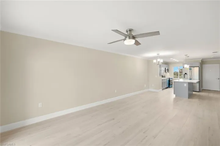 Unfurnished room with a chandelier, crown molding, baseboards, light wood finished floors, and ceiling fan