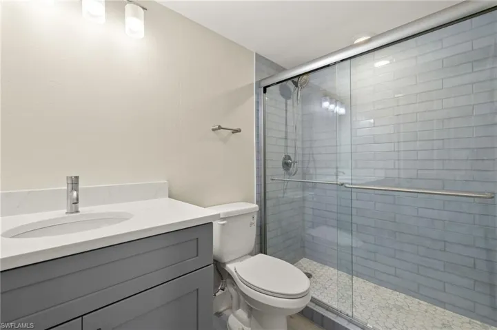 Bathroom featuring a stall shower, vanity, and toilet