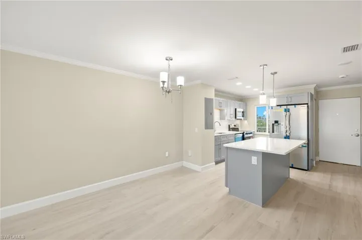 Kitchen featuring gray cabinets, stainless steel fridge with ice dispenser, a center island, a chandelier, and crown molding