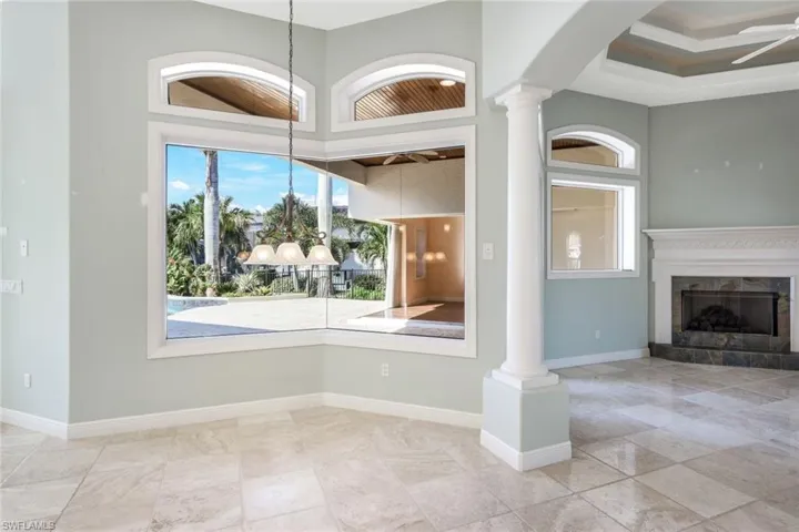 Unfurnished living room with a high end fireplace, ceiling fan, ornate columns, and light tile patterned floors