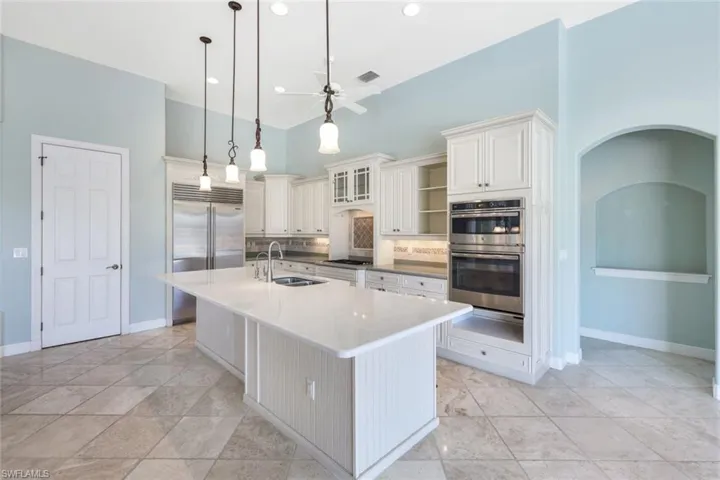 Kitchen featuring ceiling fan, a kitchen island with sink, backsplash, stainless steel appliances, and sink