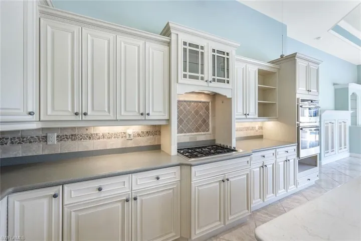 Kitchen with appliances with stainless steel finishes, light tile patterned floors, decorative backsplash, and white cabinets