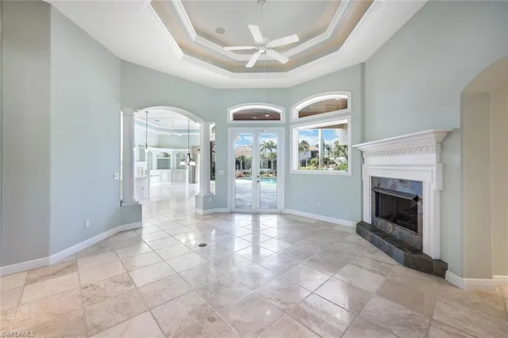 Unfurnished living room-fireplace, a tray ceiling, light tile patterned floors, and ceiling fan