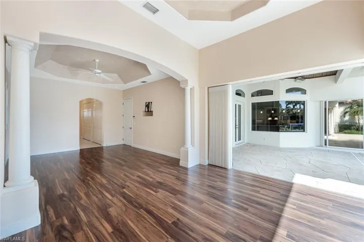 Master Bedroom featuring decorative columns, ceiling fan, hardwood / wood-style floors, and a tray ceiling