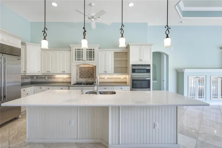 Kitchen with decorative island backsplash, light tile patterned floors, and stainless steel appliances