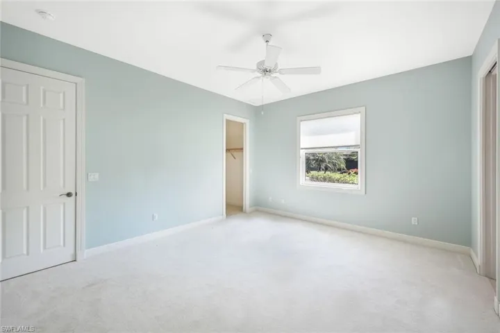 Unfurnished bedroom featuring ceiling fan, a walk in closet, and carpet flooring