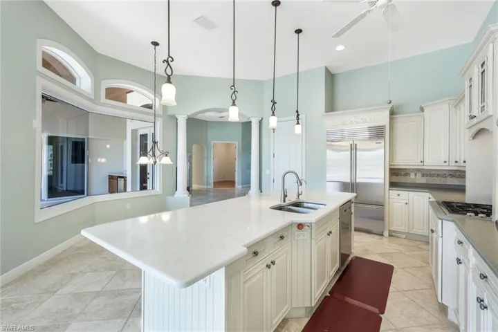 Kitchen featuring ceiling fan, sink, an island with sink, and light tile patterned floors