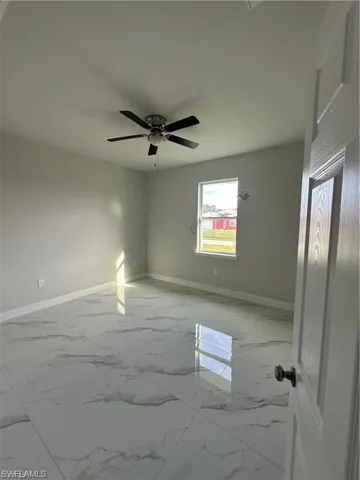 Unfurnished room with light marble finish floors and ceiling fan